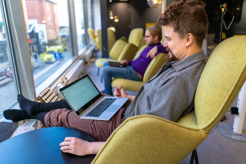 Kasvuyrityksen kaksi työntekijää tekevät töitä rennosti kannettavalla coworking-tilassa